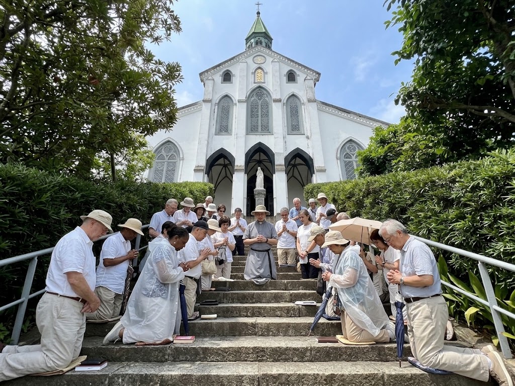 Pilgrims kneeling in prayer on the steps of a Catholic church
